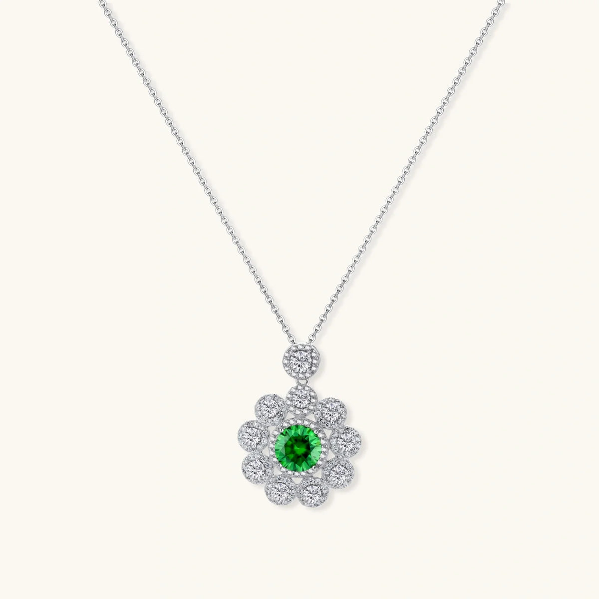Delicate sterling silver necklace with a flower-shaped pendant featuring a green centre moissanite and clear accents.