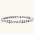 Sterling silver tennis bracelet with continuous row of brilliant moissanite stones and secure clasp closure on cream background.