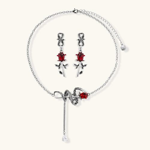 Gothic jewelry set with silver snake designs holding red enamel roses, featuring detailed leaf stems on cream background