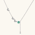 Sterling silver necklace with butterfly charms, green moissanite center stone, and teardrop crystal pendant on white background.