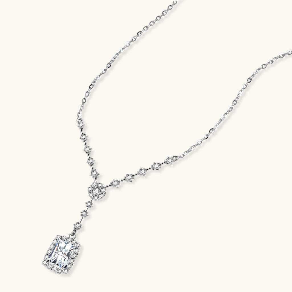 Sterling silver Y-necklace with rectangular moissanite pendant in halo setting and cascading accent stones on white background.