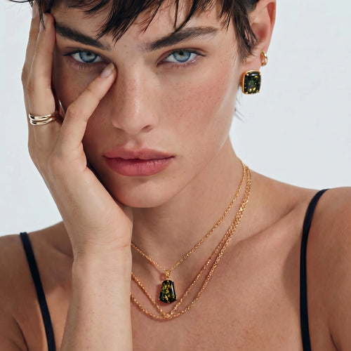 18k gold-plated necklace and earrings with green amber pendants featuring golden inclusions on cream background